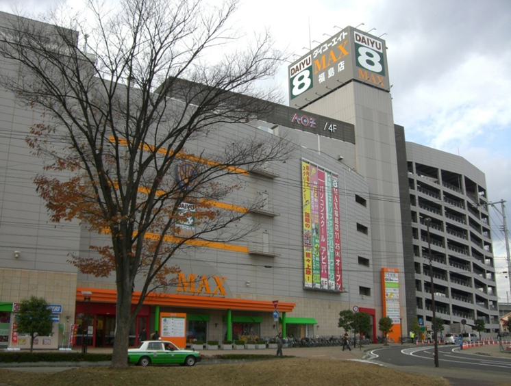 右側に立体駐車場があり、壁に懸垂幕の広告が吊るされているマックスふくしまの建物の外観写真