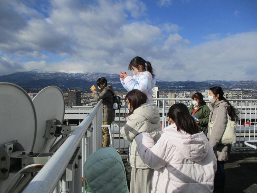 屋上から工事現場の写真を写している子供たちの写真