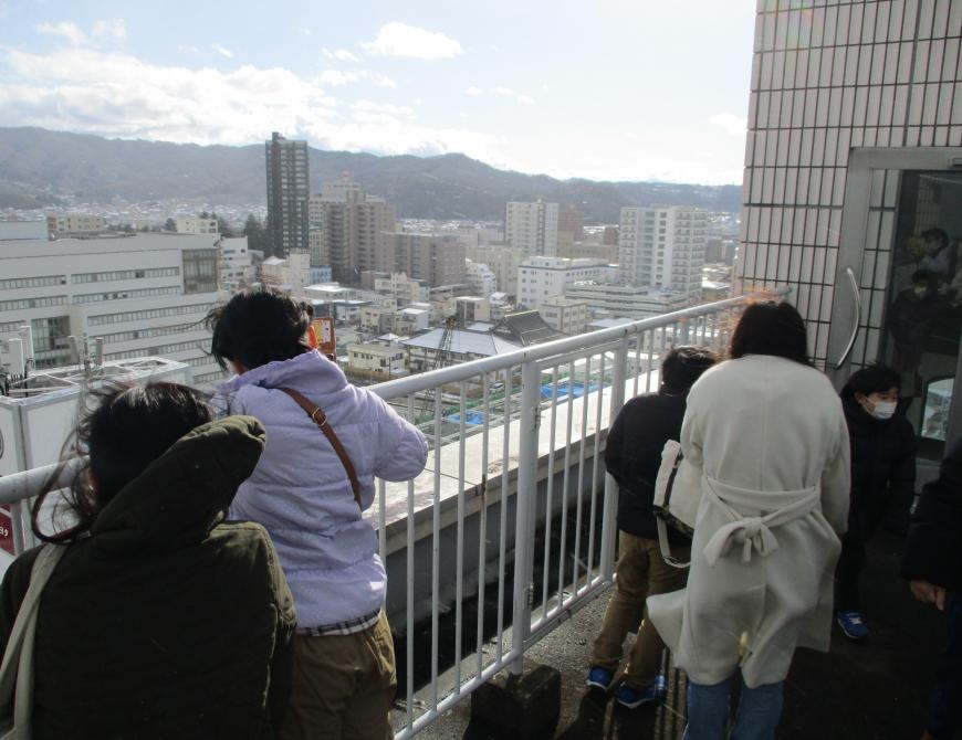 フェンスから身を乗り出すように工事現場を見ている参加者の写真