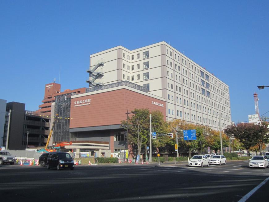 大きな道路に面しており、手前が茶色い外壁の棟、奥が白い外壁の棟に分かれている大原綜合病院の建物の外観写真