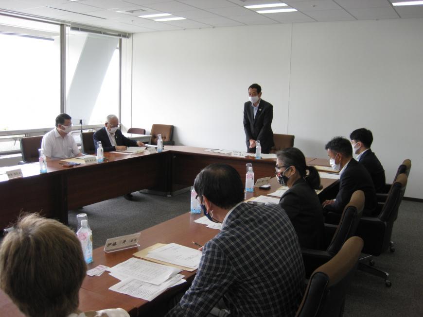 ロの字に設置された長机に関係者の人達が座り、山本副市長が立って説明をしている写真