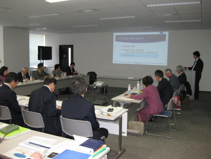 コの字型に設置されてた席に参加者の方々が座っており、前方の壁に資料が写し出され資料を見ながら審議会が行われている様子の写真