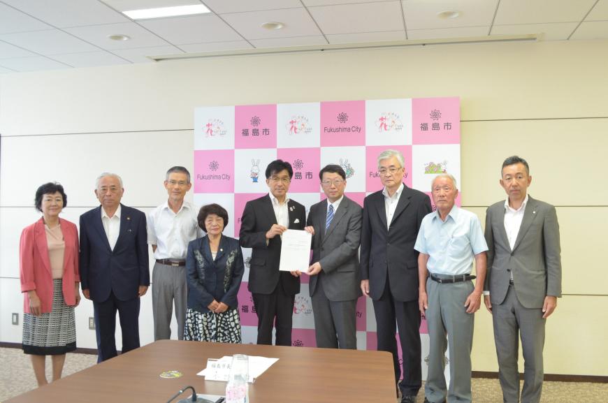 市長と関係者の男性が中央に立ち、参加者の委員の方々が集まって写っている集合写真