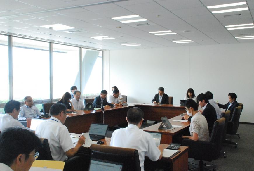 ロの字型に設置した長机の席に座った参加者たちが真剣な表情で会議を行っている様子を撮影した写真