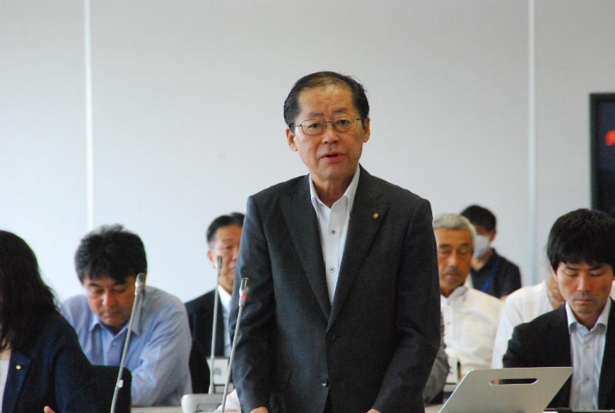 自席から立ち上がりカメラ目線で話す沢井和宏議員を撮影した写真
