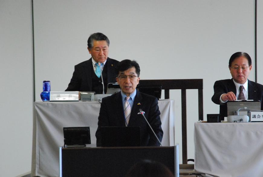 スーツを着た市長が演台に立ち話をしている写真