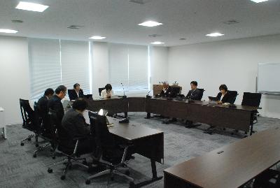 ロの字型に設置した机に委員が座り会議が行われている様子の写真