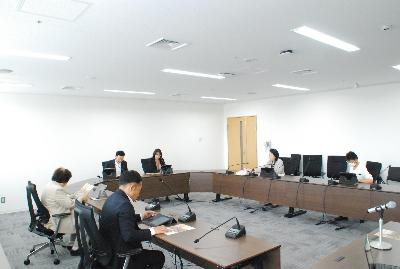 ロの字型に設置した机に委員が座り会議が行われている様子の写真