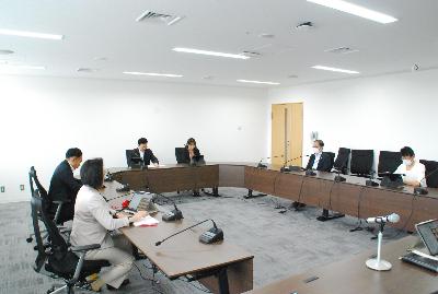 ロの字型に設置した机に委員が座り会議が行われている様子の写真