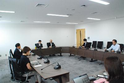 ロの字型に設置した机に委員が座り会議が行われている様子の写真