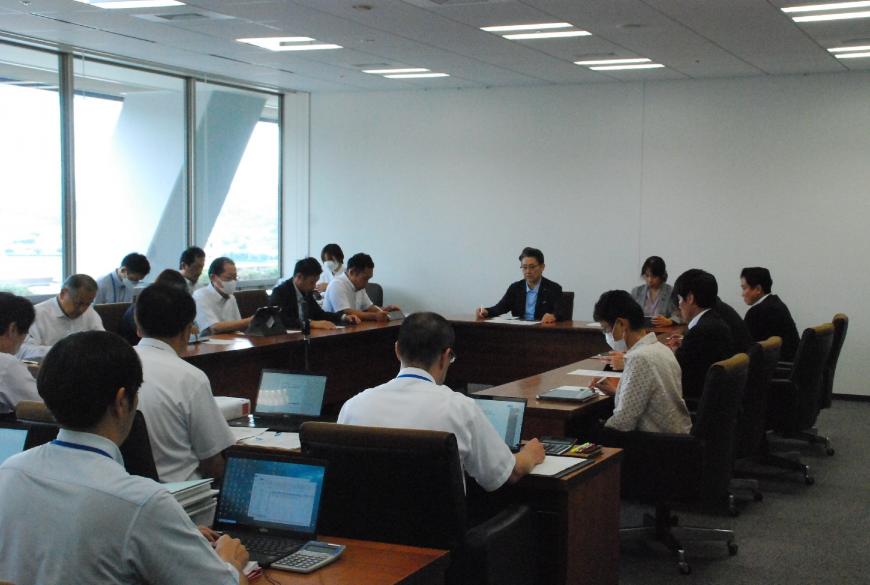 会議室で大勢の職員や役員が会議をしている様子を後ろから撮影した写真
