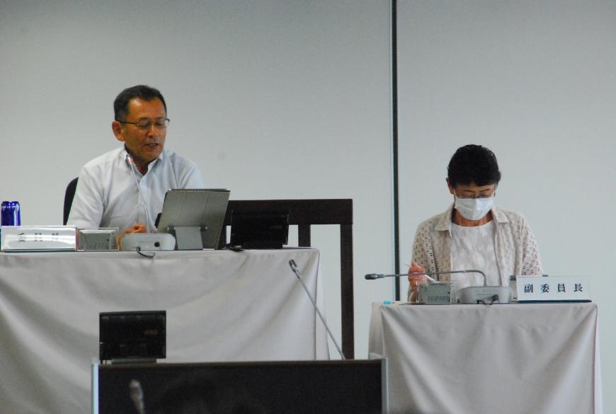 委員長の男性と副委員長の女性がタブレットを見ながら話している様子を撮影した写真