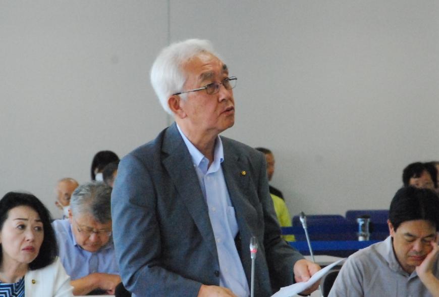 資料を持ち立って話す山田裕議員を撮影した写真