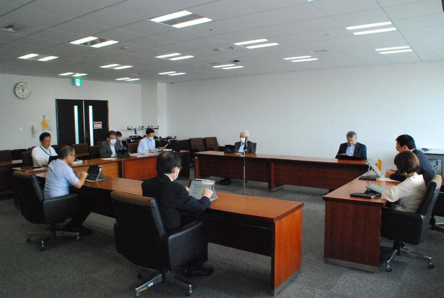 9名の役員が会議室でタブレットを使いながら議会基本条例施行状況の検証について協議している写真