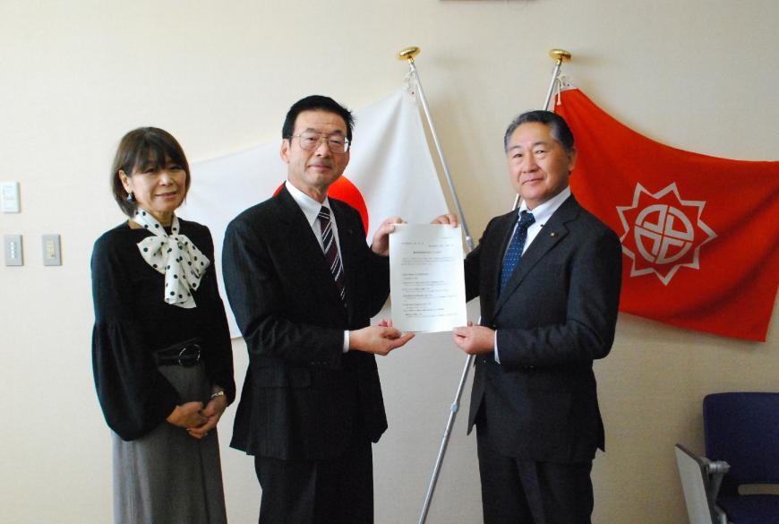 二階堂座長と萩原議長が一緒に答申書を持ち、二階堂座長の横には石山副座長が立ち記念撮影している写真