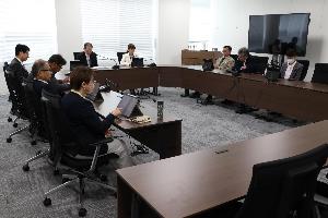 委員9名がタブレットを見ながら会議をしている写真