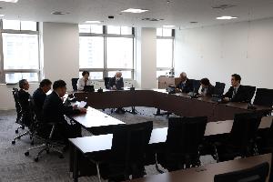 委員8名がタブレットを見ながら会議をしている写真