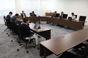 委員9名がタブレットを見ながら協議している写真