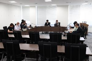 委員9名がタブレットを見ながら協議している写真