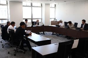 委員8名がタブレットを見ながら協議している写真