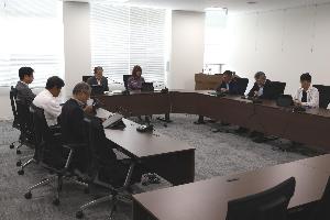 委員8名がタブレットを見ながら協議している写真