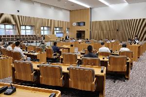 参加者が議場の座席に座って説明を受けている写真