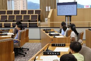 参加者が議場の座席に座って説明を受けている写真