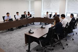 委員8名がタブレット端末を見ながら協議をしている写真