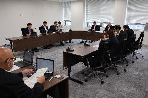 委員8名が当局から説明を受けて審査を行っている写真