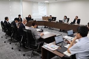 委員9名が当局から説明を受けて審査を行っている写真