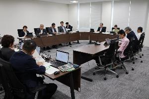 委員9名が当局から説明を受けて審査を行っている写真
