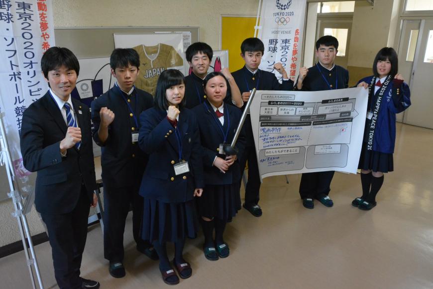 書き込んだ模造紙を手に制服姿の参加男女学生がガッツポーズをし記念撮影している写真