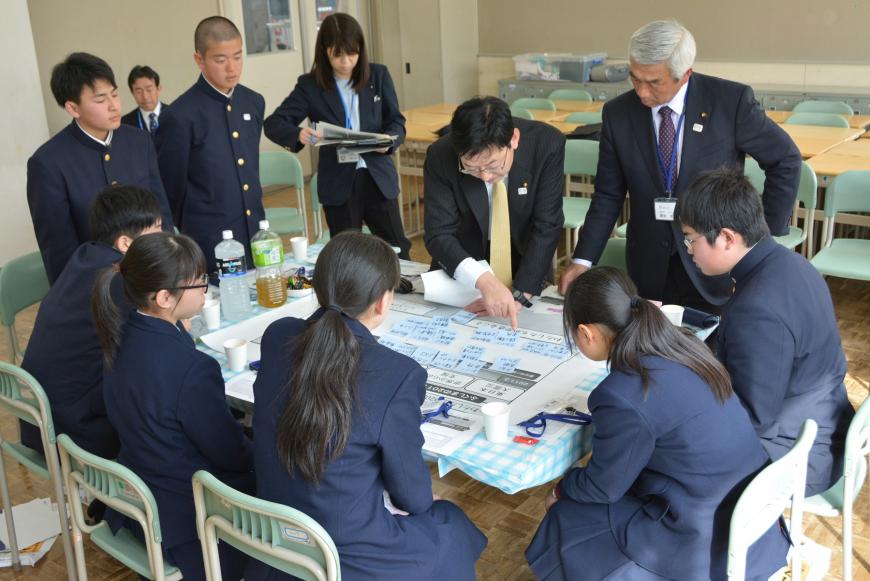 テーブルに置かれた模造紙に記載した付箋が貼られ、参加された議員の方が指を差しながら話をしている写真