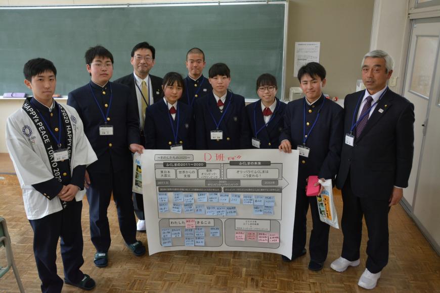 半円形を描くように参加した議員の方と学生が立ち、話し合いでまとめ、付箋がたくさん張られた模造紙を中央の学生が持ち記念撮影している写真