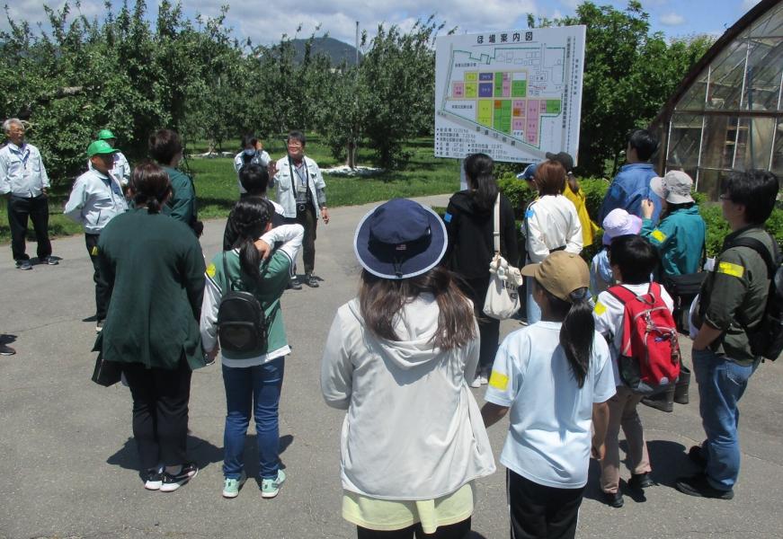 案内図が載った大きな看板の前に集まり話を聞いている参加者たちの写真