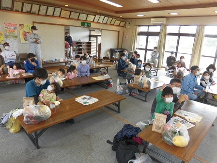 たくさんの参加者が席に座り、何人かの子どもたちが手を挙げている写真