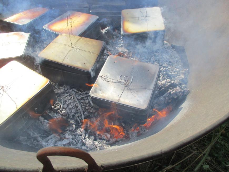 炭化器の中にある7つの缶が黒っぽく変色し、煙を上げている写真