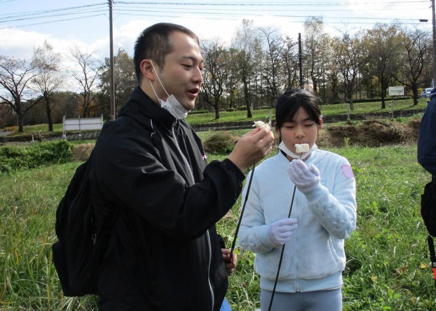 竹串の先のチーズを食べている参加者の写真