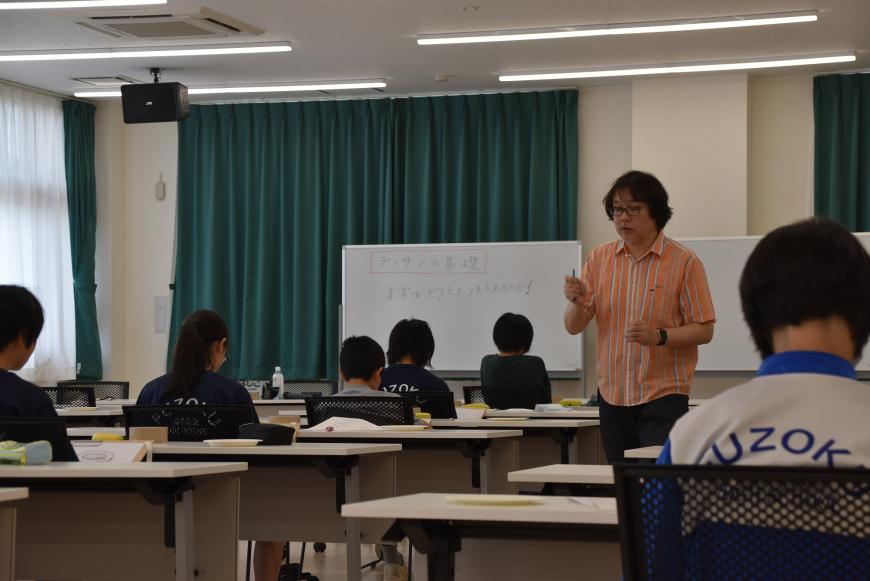 齋氏が生徒の間を歩きながら話をしている様子の写真