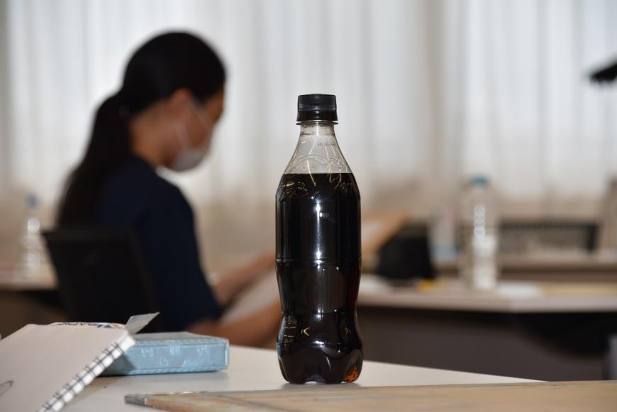 飲み物の入ったペットボトルが机の上に置かれている写真