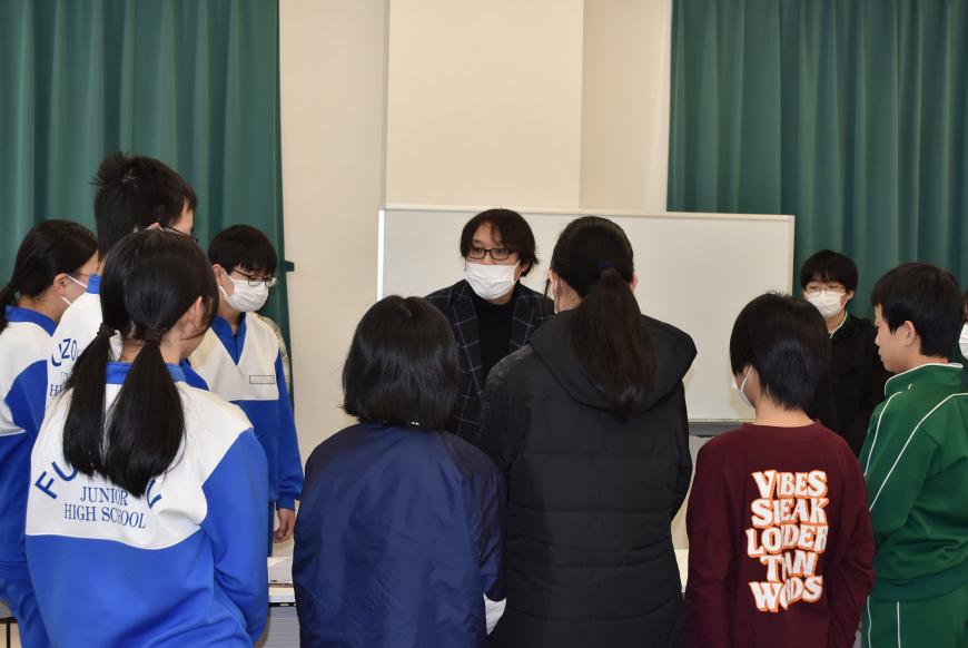 齋氏の周りに生徒の皆さんが集まり、説明を聞いている様子の写真