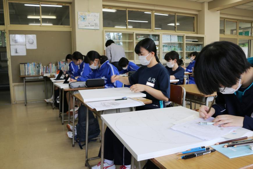 自席に座っている生徒の皆さんが集中して絵を描いている教室の様子を、横から写した写真