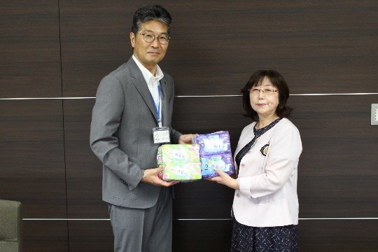 市長と女性が寄贈していただいた生理用品を持って記念撮影している写真