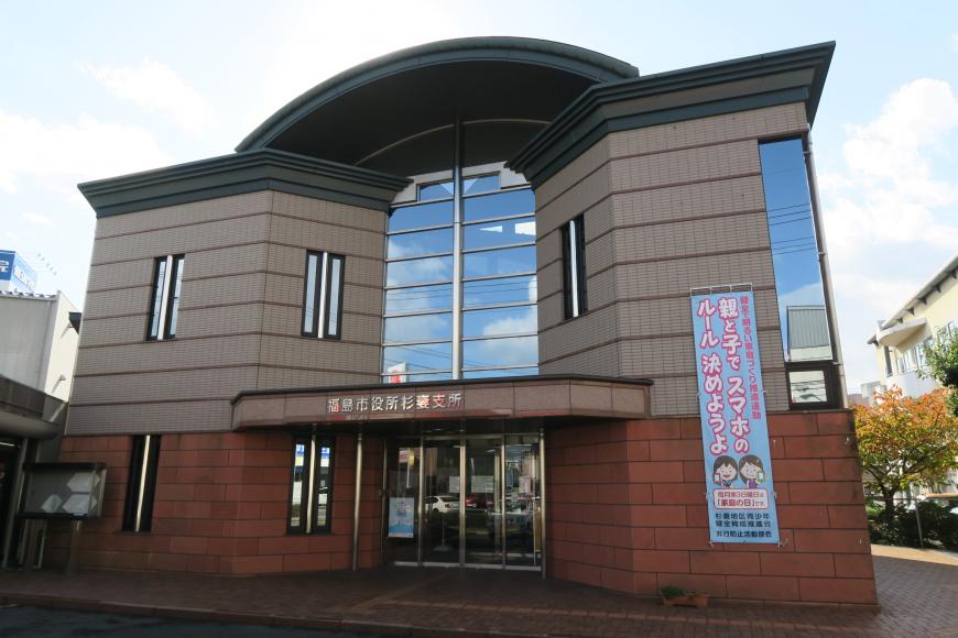 茶色とレンガ調上下に分かれた外壁で、建物の中央に玄関がありガラス張りの窓がある杉妻支所の外観写真