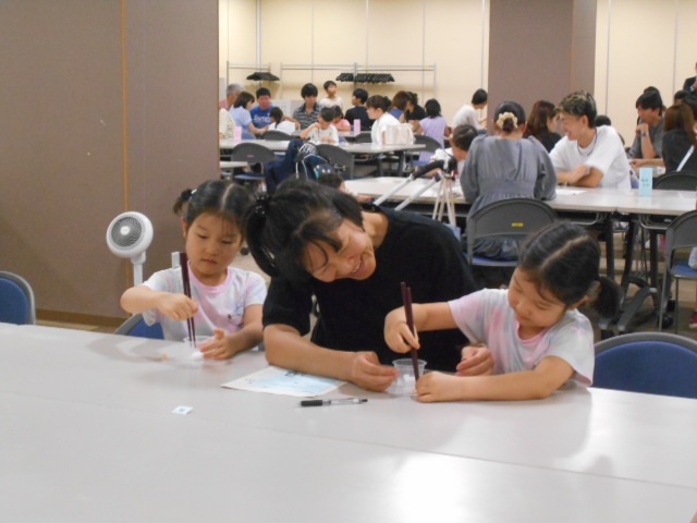 お母さんと子どもが箸を持つ練習をする写真