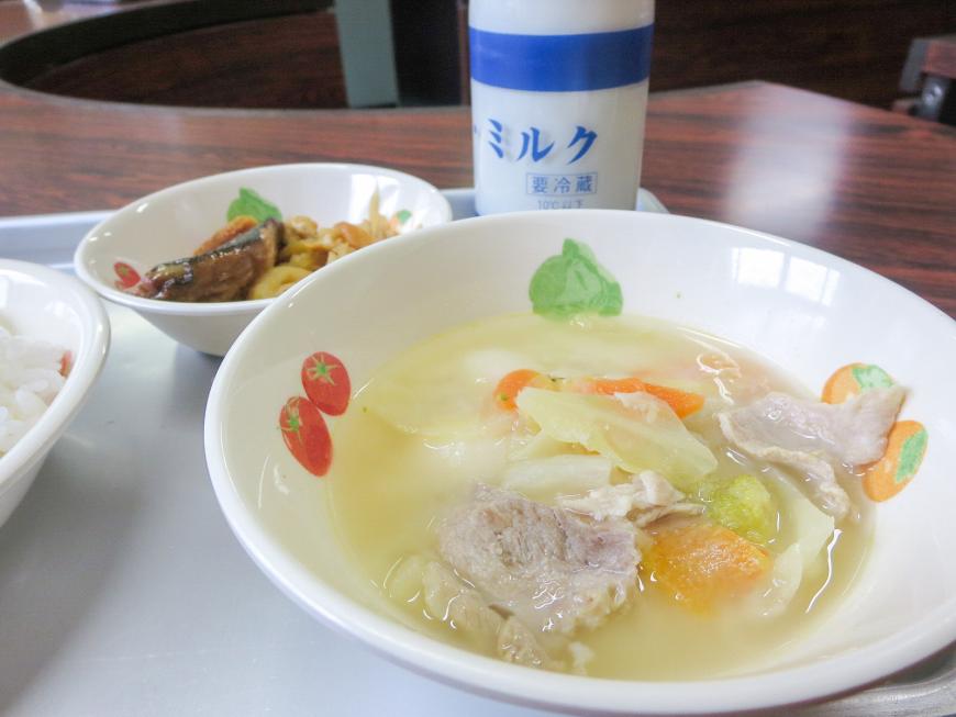 瓶に入った牛乳、小さめのお皿に入ったおかずと野菜とお肉が入ったスープがトレーの上に置かれている写真