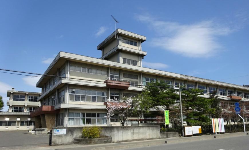 黒いフェンスとコンクリートの門で道路と隔たれた敷地に2棟の3階建ての校舎がたっている岡山小学校の外観写真