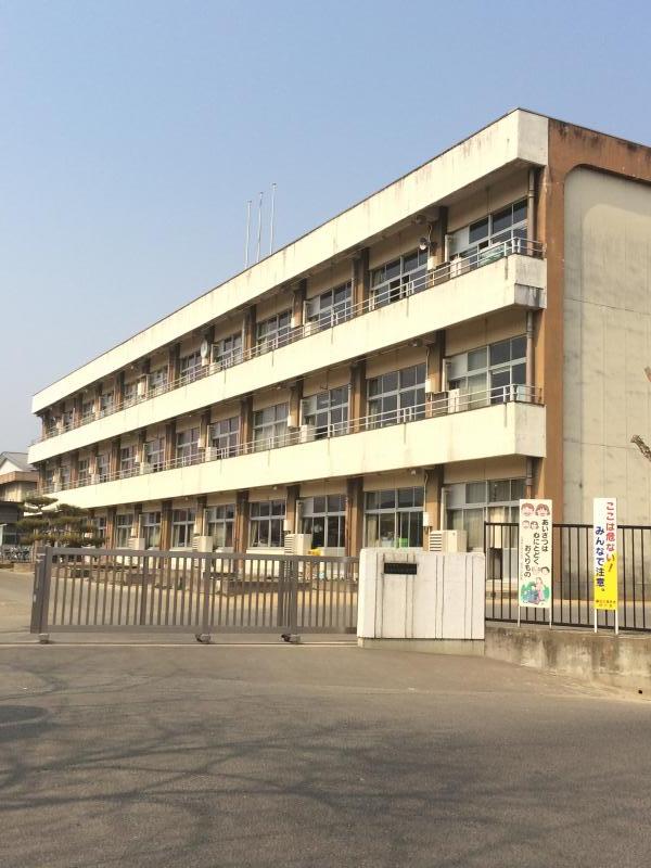 門の中のコンクリートの敷地に3階建ての校舎が建っている鎌田小学校の外観写真