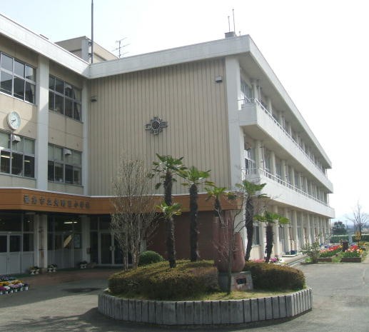 低木などが植えられた丸い植栽の先に、3階建ての校舎が建っている矢野目小学校の外観写真