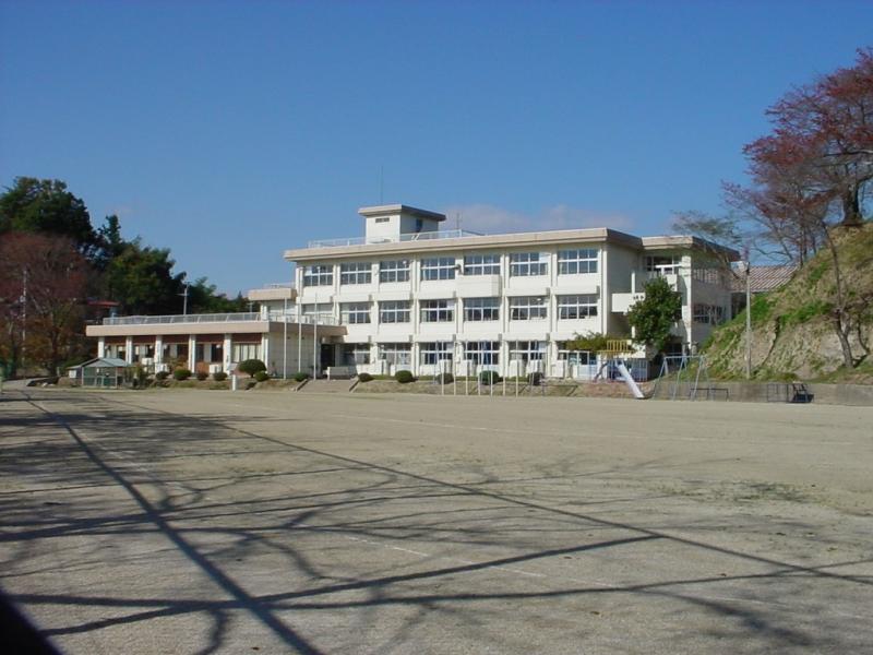 広い校庭の奥に1階建てと3階建ての建物が併設された校舎がある立子山小学校の外観写真